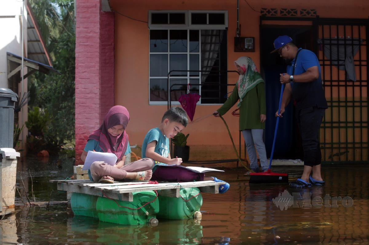 Nur Sofea bersama adiknya membuat modul yang disediakan guru bagi pelajar yang terjejas akibat banjir untuk menjalani pengajaran dan pembelajaran di rumah (PdPR) di rumahnya di Parit Karjo, Batu Pahat, Johor. FOTO NUR AISYAH MAZALAN