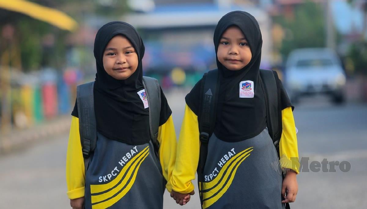 Gelagat pasangan kembar, Nur Atiah Mohd Idham (kiri) dan Nur Ayra murid Tahun Satu hadir pada hari pertama persekolahan di Sekolah Kebangsaan (SK) Pusat Chabang Tiga. FOTO GHAZALI KORI