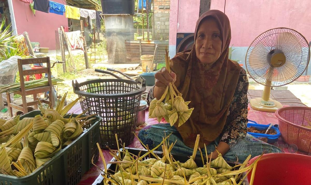 Rahimah menunjukkan ketupat palas yang sudah siap dibungkus ketika ditemui di rumah mereka di Kampung Kubang Palas, Banggu. FOTO HAZIRA AHMAD ZAIDI