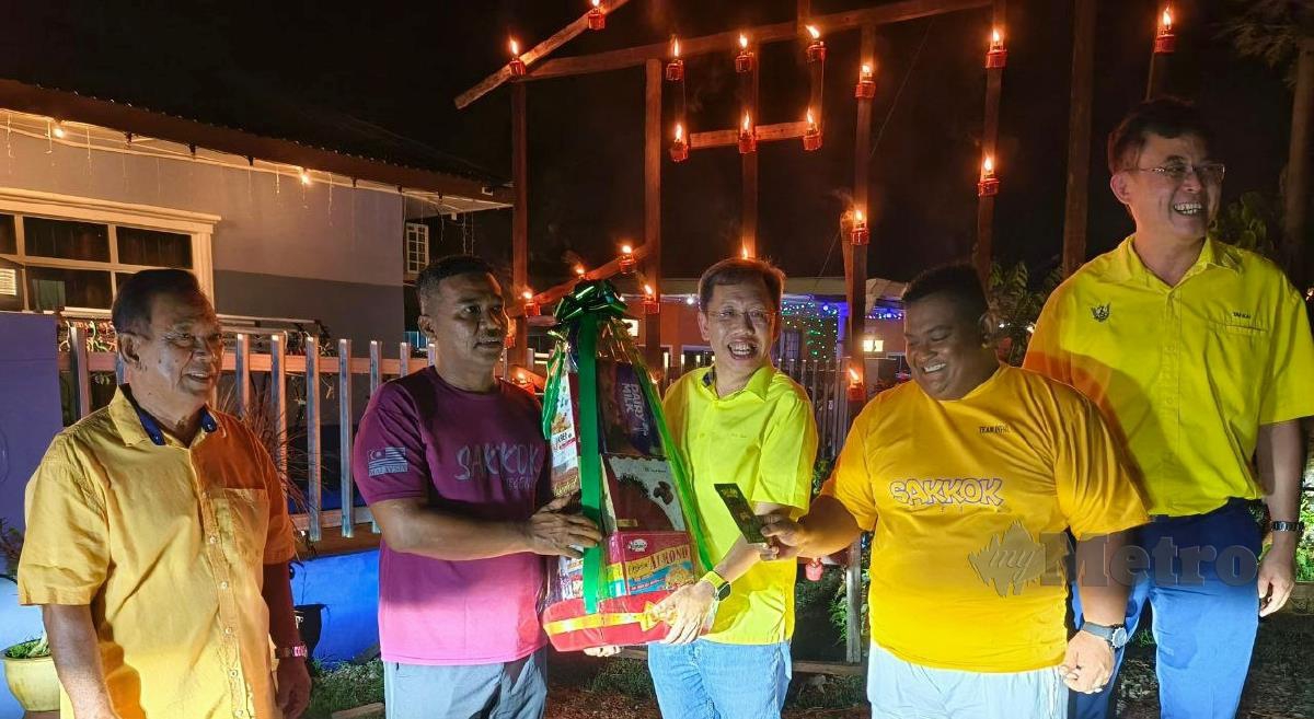 SIM (tengah) menyampaikan hadiah kepada Simi Solhi, pemenang pertandingan bertuntung Kampung Sinar Budi Baru, Sarawak. FOTO Mohd Roji Kawi.