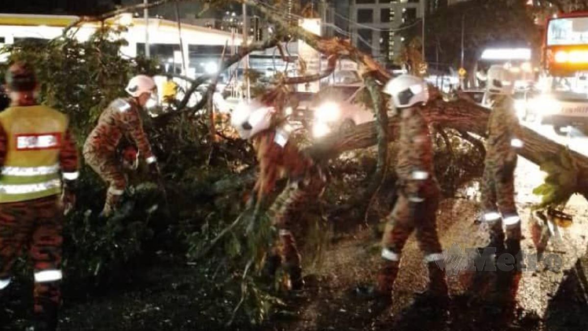 ANGGOTA bomba mengalihkan pokok tumbang yang menghempap sebuah kereta di Jalan Ampang. FOTO Ihsan Bomba 