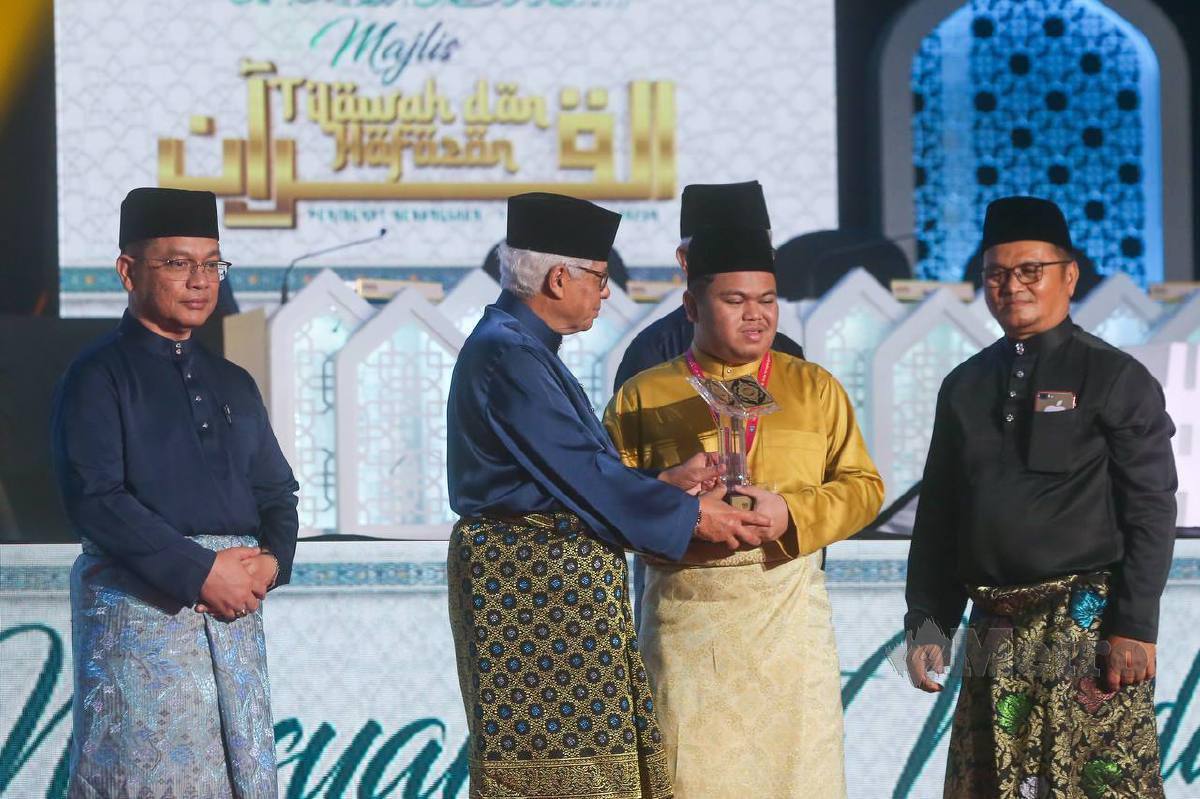 AHMAD Fuzi (dua dari kiri) menyampaikan hadiah kepada Muhammad Qayyim sambil diperhatikan Dr Mohd Nai'im (kiri) dan bapa qari itu Saimi Yusoff, 58. FOTO Danial Saad.