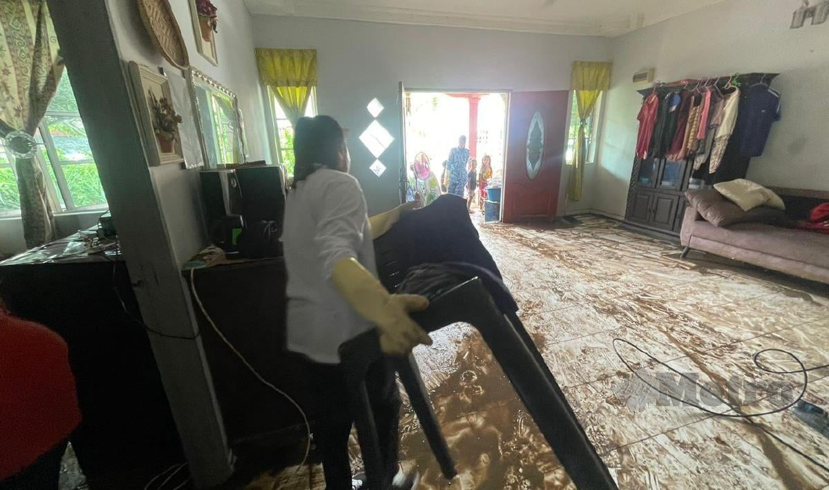 Penduduk dibantu anggota Angkatan Pertahanan Awam Malaysia (APM) membersihkan rumah yang dimasuki air akibat kejadian banjir yang berlaku di Kampung Chinggong,malam kemalrin. FOTO IHSAN APM