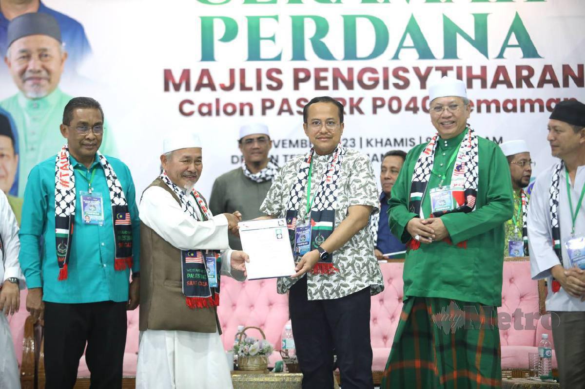 TUAN Ibrahim (dua kiri) menyampaikan Watikah Perlantikan Calon PAS bagi PRK Parlimen Kemaman kepada Dr Ahmad Samsuri. FOTO Ghazali Kori.