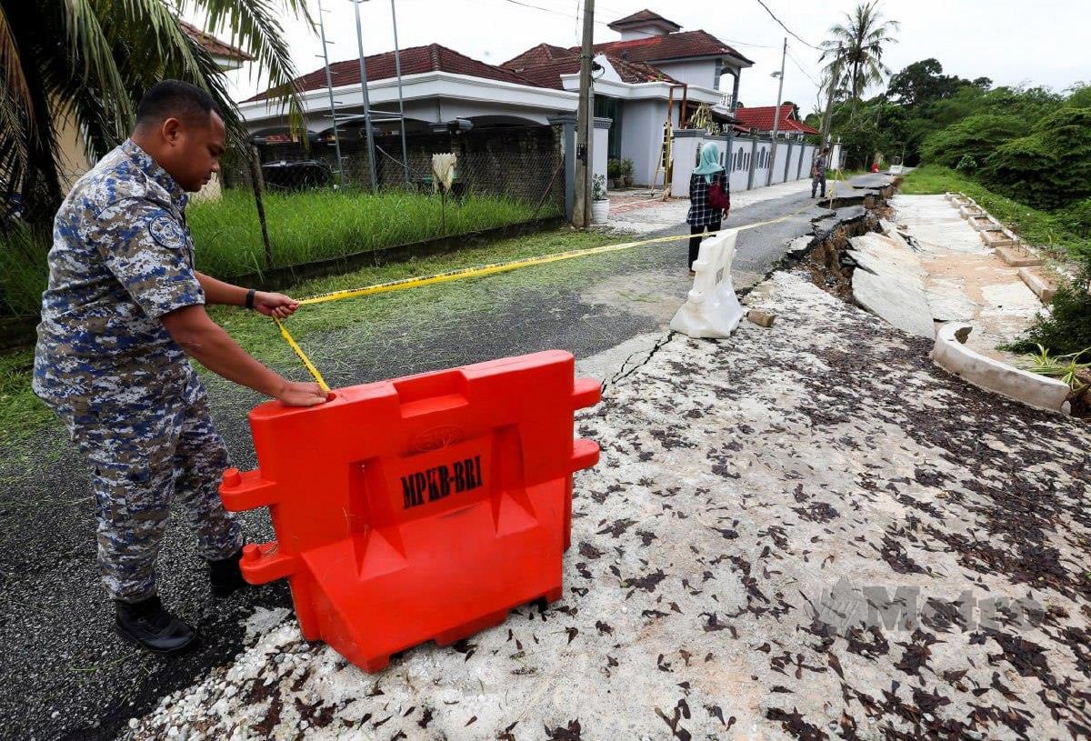 ANGGOTA penguat kuasa Majlis Perbandaran Kota Bharu memeriksa kawasan jalan yang runtuh. FOTO Nik Abdullah Nik Omar