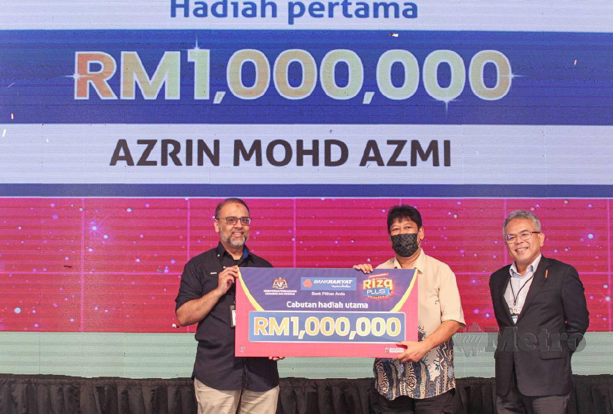 MOHD Irwan (kiri) menyerahkan replika cek bernilai RM1 juta kepada wakil pemenang, Aznul Haidi Mohd Azmi, 59, iaitu adik kepada Mohd Azrin. FOTO Aziah Azmee