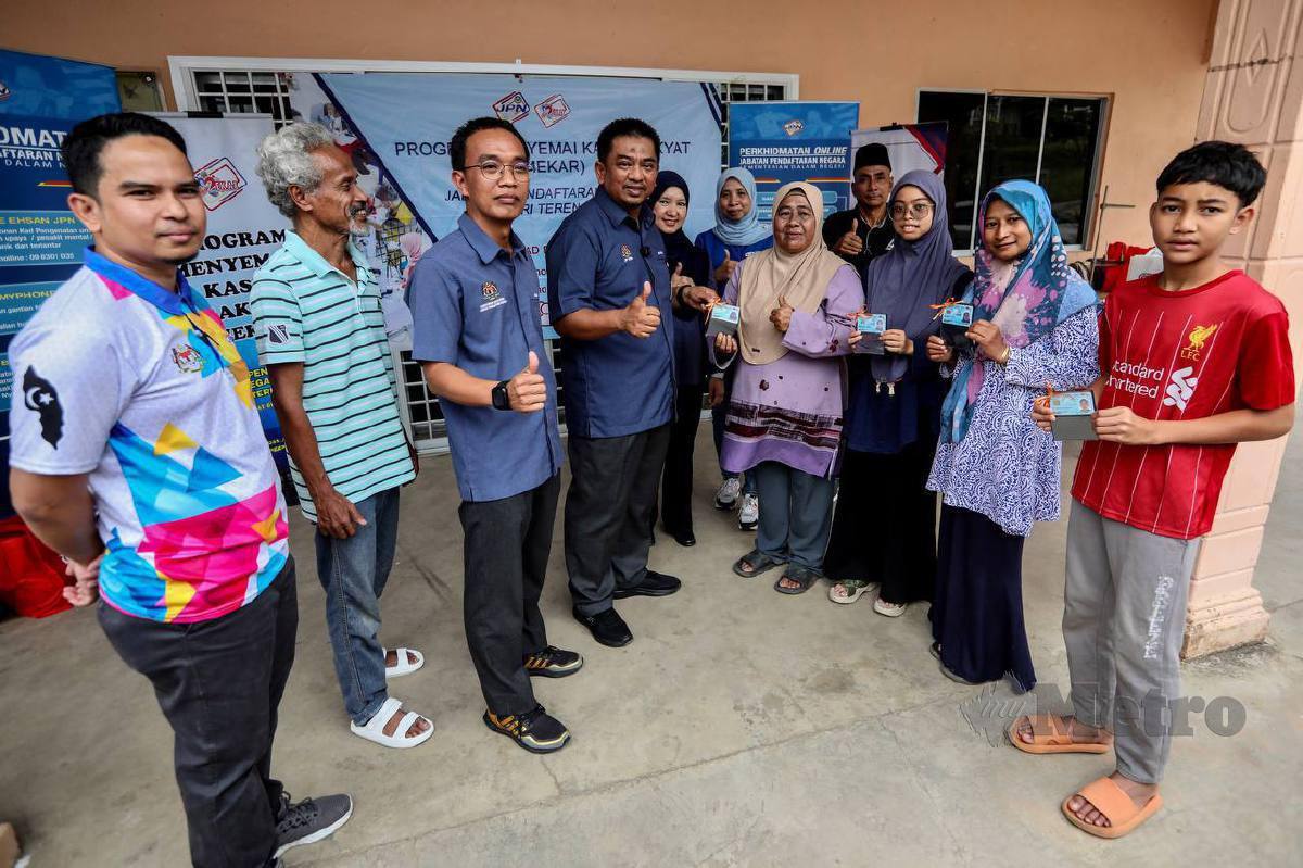 BADRUL Hisham (empat kiri) menyerahkan kad pengenalan kepada mangsa banjir di Kampung Pasir Raja, Dungun. FOTO Ghazali Kori