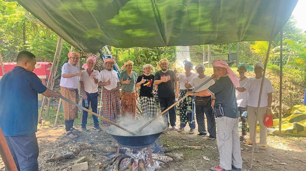 MOHD Shukri (baju putih kiri) bersama penduduk Bayu Damansara terbabit aktiviti memasak bubur asyura.