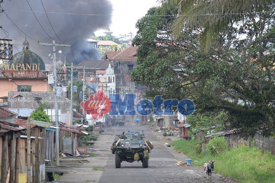 Kenderaan berperisai pasukan marin Filipina bergerak dari kawasan pertempuran dengan kepulan asap akibat bedilan roket dari helikopter di belakang. - Foto AFP