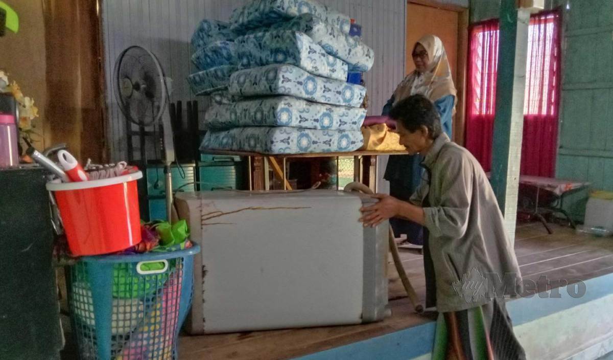 MANSOR Ali bersama isterinya Maznah menyimpan barangan di dalam rumah di ruang yang lebih tinggi. FOTO Nazdy Harun