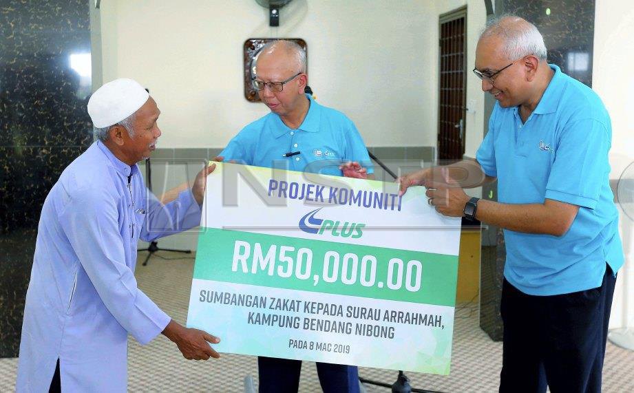 AZMAN (kanan) menyerahkan sumbangan zakat kepada Pengerusi Surau Ar-Rahmah, Abdul Wahab Daud, 69,  sambil disaksikan Aziz. FOTO Abdullah Yusof