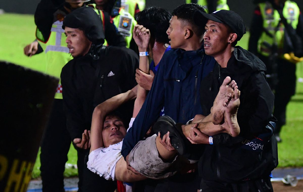SEORANG penyokong yang pengsan dibawa keluar stadium. FOTO AFP