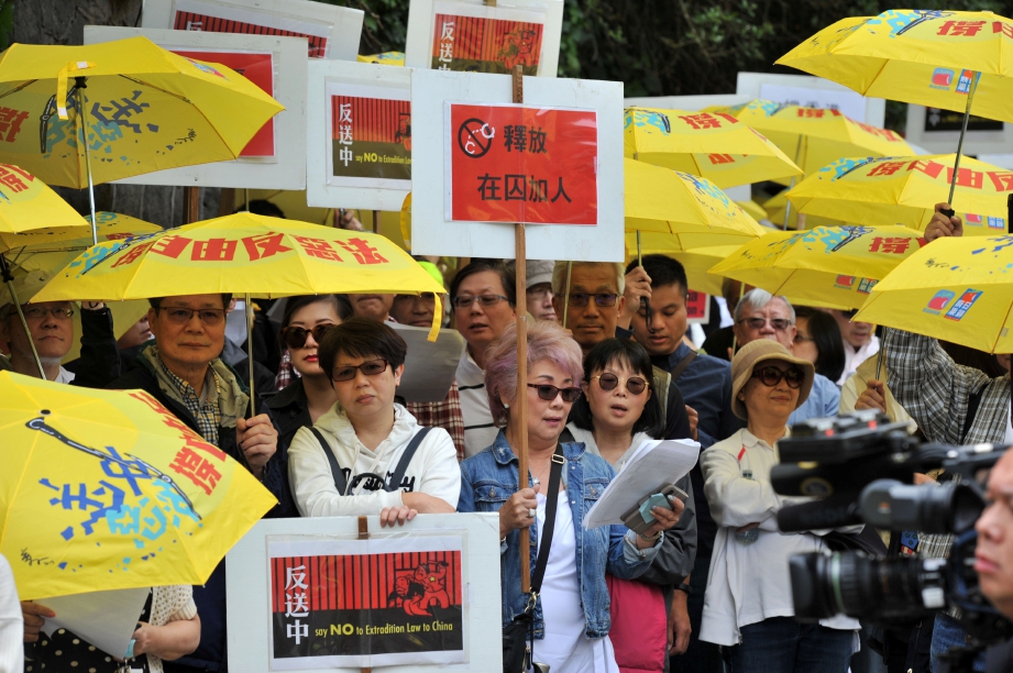 PENUNJUK perasaan membawa sepanduk dan payung kuning berhimpun di luar konsulat China, Vancouver.
