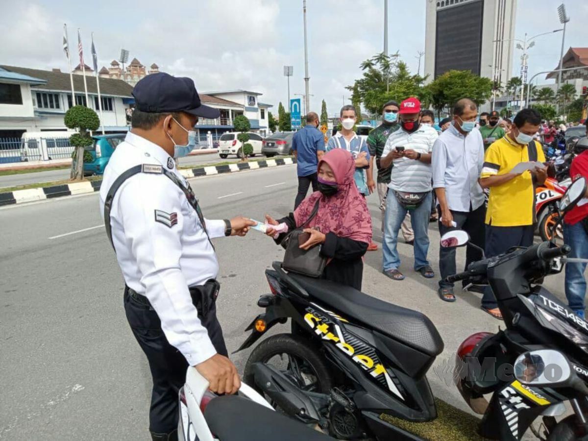 Anggota Polis Trafik melayan seorang warga emas yang hadir untuk menjelaskan bayaran kompaun di Balai Polis Trafik IPD Kuala Terengganu, hari ini. FOTO BAHAROM BAKAR 