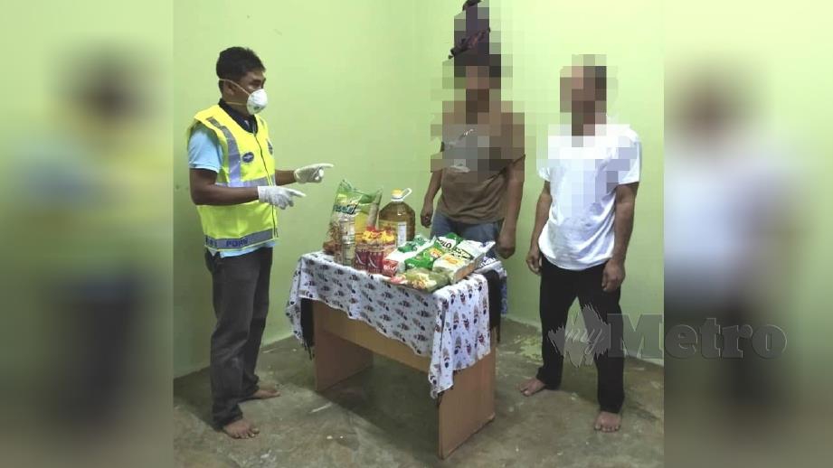 Anggota polis menyediakan bekalan makanan kepada dua lelaki yang menjalani PPT di Kuala Klawang, Jelebu semalam. Foto Abnor Hamizam Abd Manap