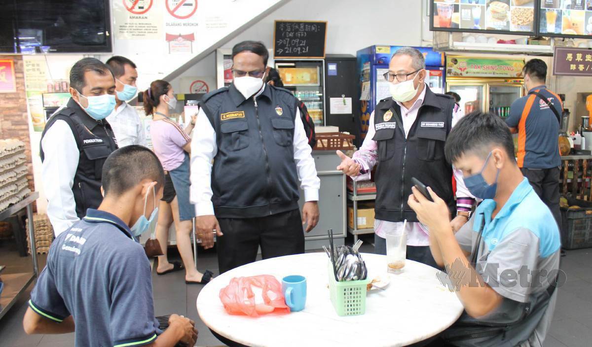 S VEERAPAN (tengah) dan Dr Mohammad Faid (dua kanan) membuat pemeriksaan terhadap pengunjung di sebuah restoran dalam operasi Akta 342 di Seremban 2. FOTO Mohd Amin Jalil