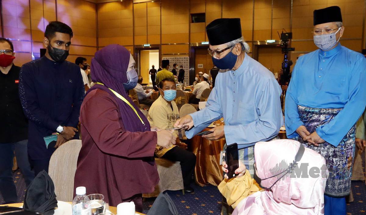 ANNUAR (kanan) memerhatikan Mohd Radzi menyampaikan sumbangan kepada penerima di majlis Prihatin Ramadan Wilayah Persekutuan di Putrajaya. FOTO Mohd Fadli Hamzah