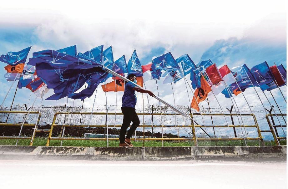 SEORANG petugas BN kelihatan membawa bendera untuk menyemarakkan lagi PRN Sabah. FOTO Bernama.