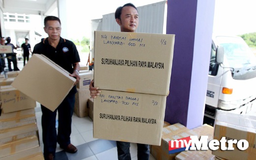 PETUGAS Suruhanjaya Pilihan Raya (SPR), mengangkat kotak barang keperluan untuk dihantar ke kawasan sekitar Kuching yang akan digunakan pada Pilihan Raya Negeri Sarawak Ke-11 pada 7 Mei ini. FOTO Khairull Azry Bidin