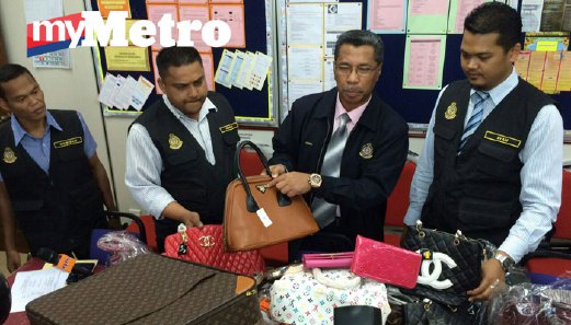 Jamal (tengah) menunjukkan sebahagian tas tangan tiruan yang dirampas di Padang Besar semalam. FOTO Hafizuddin Mohd Safar