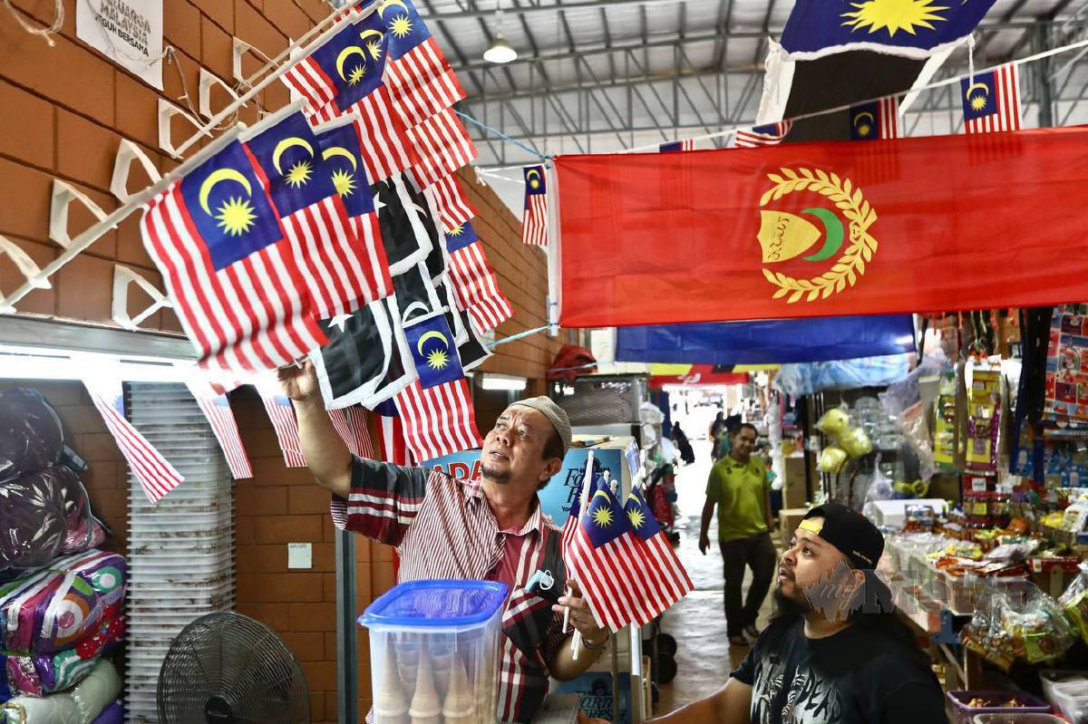 Zakaria (kiri) bersama peniaga di Pasar Kedai Payang memasang jalur gemilang dan bendera setiap negeri bagi menzahirkan rasa cinta kepada tanah air sempena menyambut Hari Kebangsaan dan Hari Malaysia. FOTO GHAZALI KORI