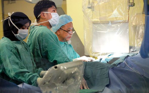 DR WAN Azman (kanan sekali) ketika menjalankan pembedahan angioplasti seorang pesakit sambil dibantu pakar kardiologi lain.