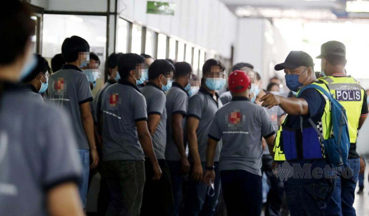 ANGGOTA polis melakukan pemeriksaan rekod apikasi MySejahtera terhadap pekerja dan lebih kapasiti pekerja yang hadir dalam Op Patuh di sebuah kilang cetak. FOTO Mikail Ong