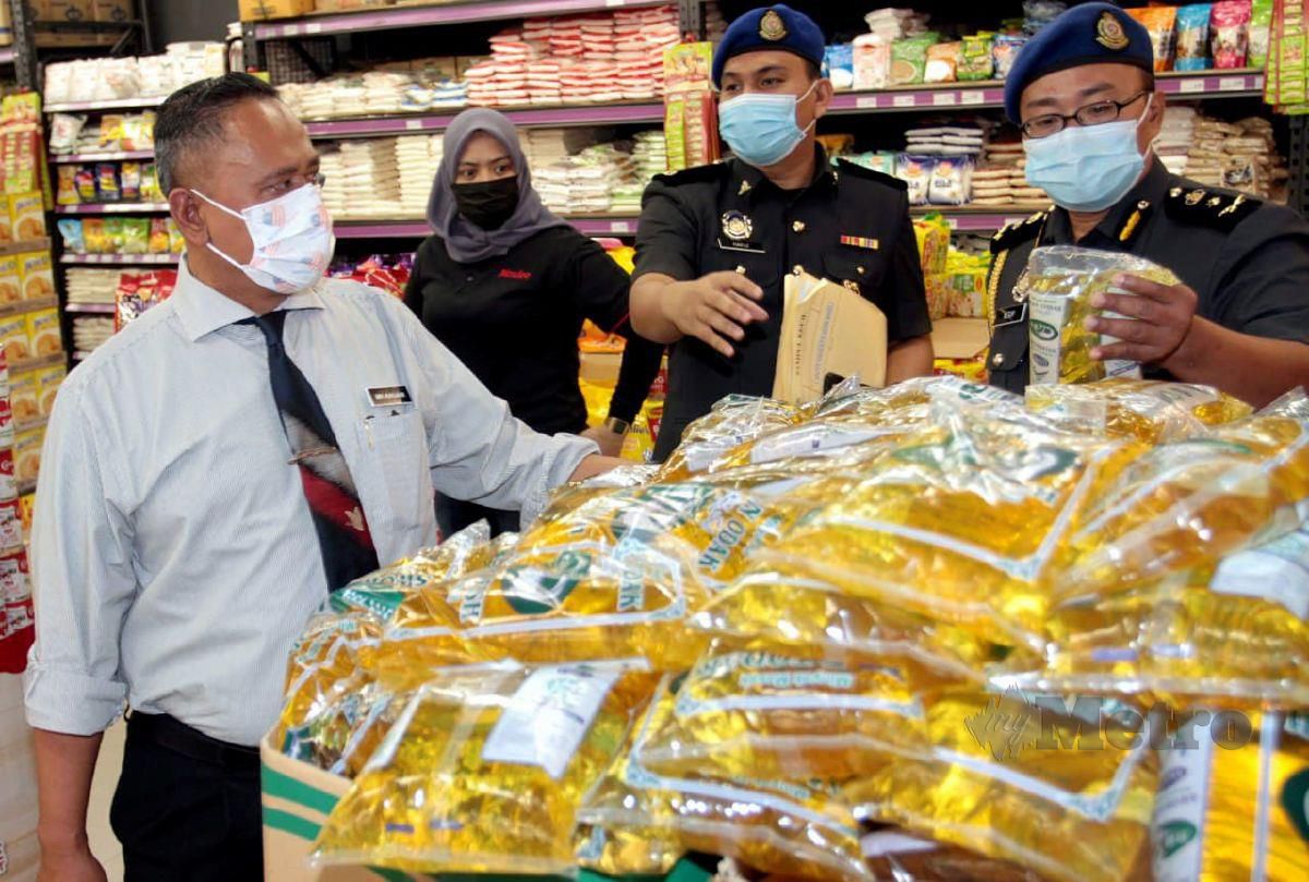 Mohd Hairul Anuar (kiri) melihat paket minyak masak bersubsidi yang dijual di sebuah pasar raya ketika membuat pemantauan di Johor Bahru. FOTO Zain Ahmed