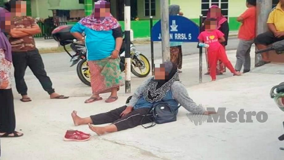 Mangsa yang mengalami kecederaan terduduk di lokasi kejadian di kawasan Rumah Rakyat Sungai Layang di Rembau, selepas diragut seorang penunggang motosikal, hari ini.
