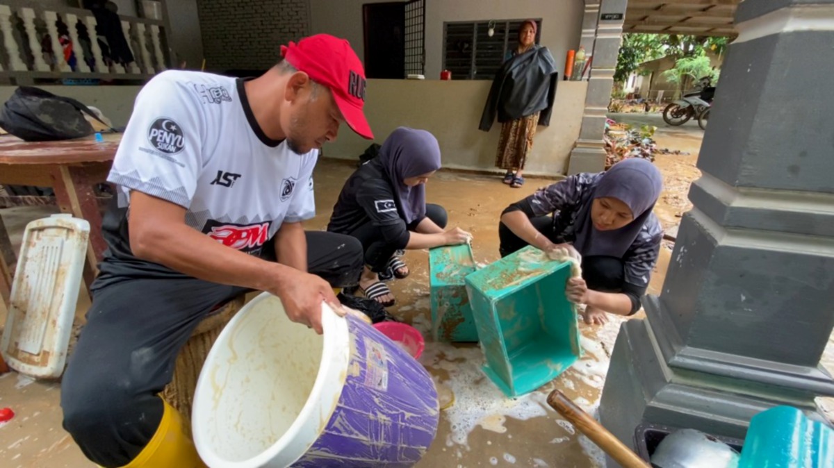 Pemain ragbi Terengganu membersihkan peralatan mangsa banjir di Hulu Terengganu.