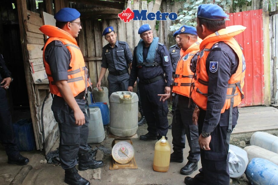 Zulkafli (tengah) memeriksa sebahagian tong minyak petrol yang dirampas. FOTO Nik Abdullah Nik Omar
