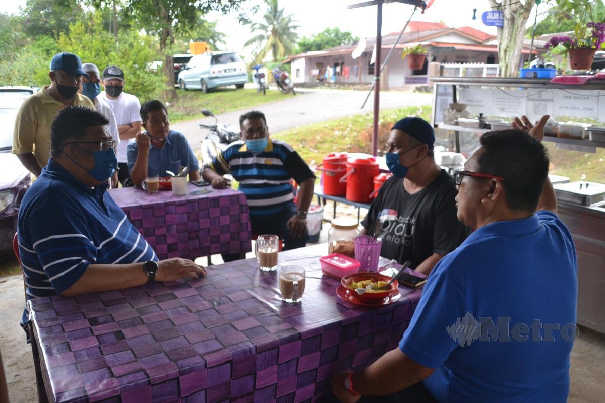 AB Rauf (kiri) beramah mesra dengan anggota komuniti ketika menikmati sarapan di warung kopi Kampung Ayer Limau, Masjid Tanah. FOTO HASSAN OMAR