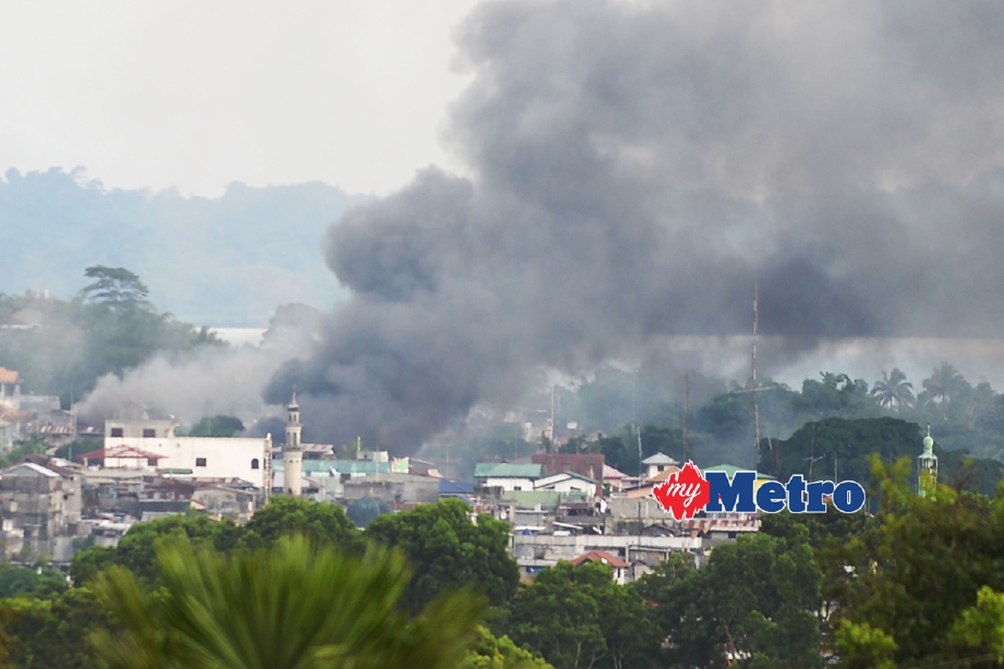 Kepulan asap dekat pasar awam Marawi selepas helikopter tentera Filipina melepaskan bedilan roket terhadap kedudukan militan. - Foto AFP 