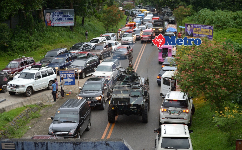 Kenderaan tentera terpaksa melalui di celah-celah kenderaan orang ramai yang melarikan diri dari Marawi. - Foto AFP