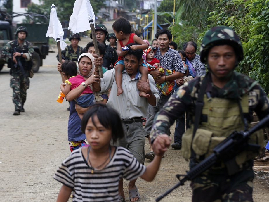Penduduk yang terperangkap di kawasan pertempuran diiring keluar oileh tentera di Marawi. - Foto EPA