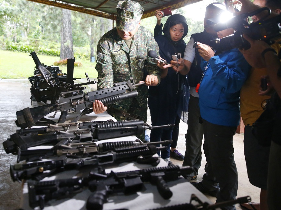 Seorang pegawai tentera Filipina memeriksa sebahagian senjata api berkuasa tinggi, termasuk mesingan 50 kaliber yang digunakan militan di Marawi. - Foto AP 