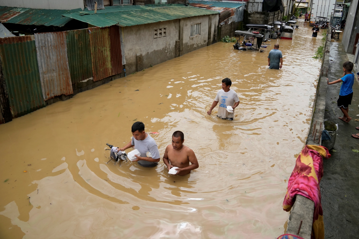 PENDUDUK meredah banjir selepas Taufan Noru di bandar San Miguel, wilayah Bulacan. FOTO AP 