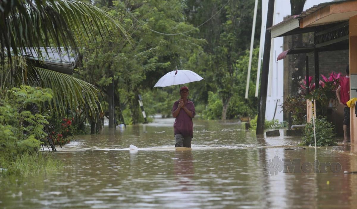 SEORANG penduduk berjalan meredah banjir di Kampung Batu 24. Kuala Berang.  FOTO Ghazali Kori 