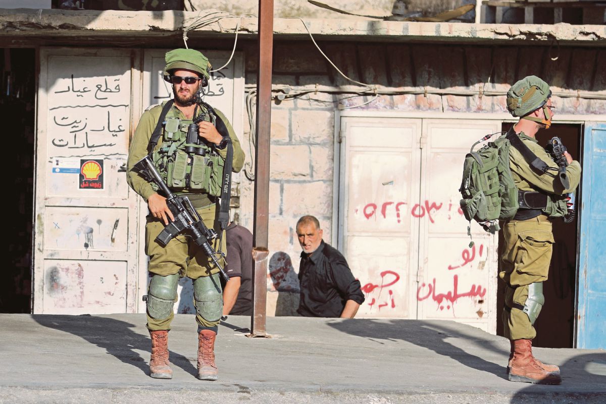 TENTERA rejim Israel di luar sebuah kedai milik penduduk Palestin di Huwara, Tebing Barat. FOTO Reuters