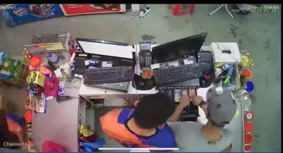 Rakaman CCTV menunjukkan suspek (kanan) mengambil wang tunai di kaunter pasar mini di Kampung Baru, Sungai Tiang selepas penjaga kaunter pasar mini itu (kiri) enggan menyerahkan lesen dan Mykad. FOTO Ihsan Pembaca