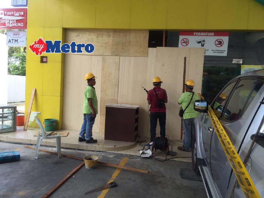 Pekerja membaiki pintu kaca stesen minyak di Putra Heights yang dirempuh penjenayah, pagi tadi. 