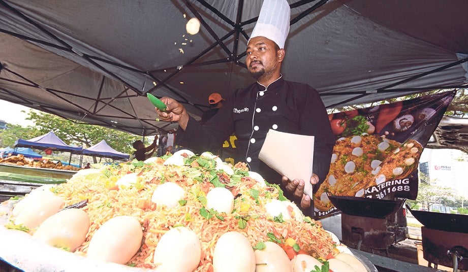 KAMARUDIN dengan teknik melambung telur rebus ketika membungkus nasi beriani di bazar Ramadan.