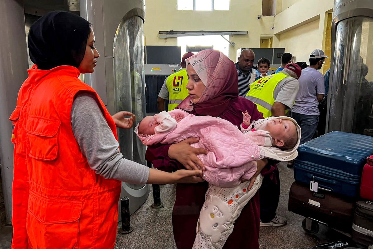 WANITA membawa dua bayi ketika melalui lintasan Rafah untuk memasuki Mesir. FOTO AFP 