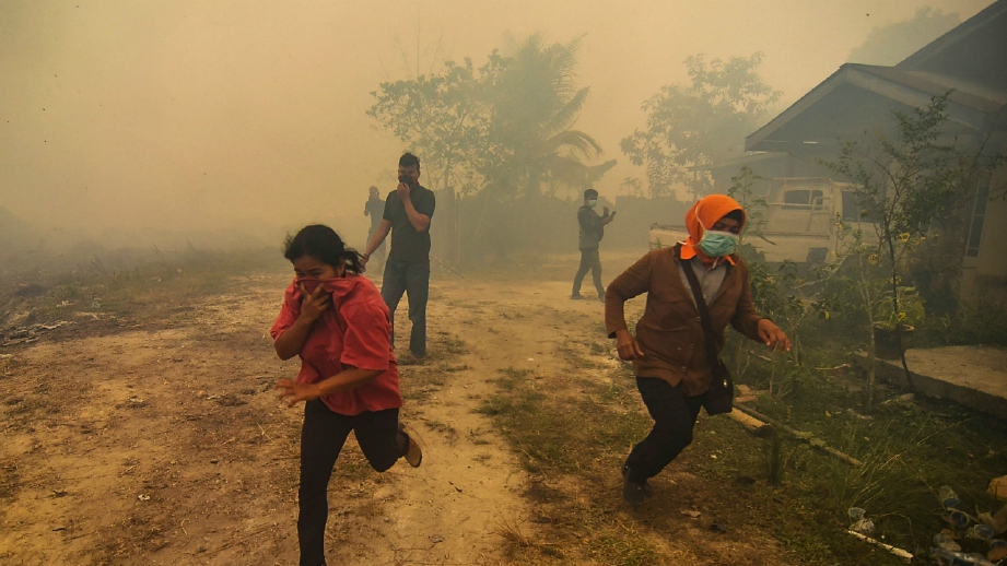 PENDUDUK terjejas jerebu akibat kebakaran hutan berhampiran kampung mereka di Kampar, Riau. FOTO AFP 