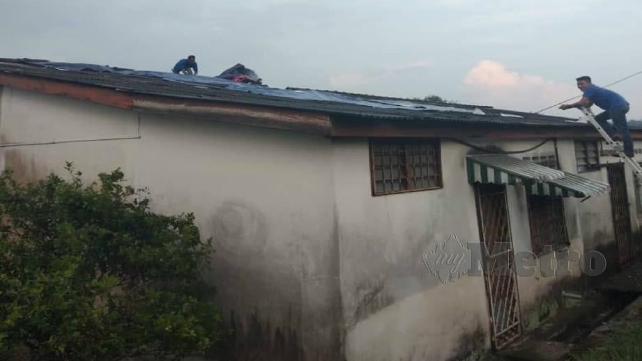 Penduduk membaiki bumbung rumah yang diterbangkan dalam kejadian ribut di Taman Desa Rhu dekat Sikamat di Seremban hari ini. Foto Ihsan APM