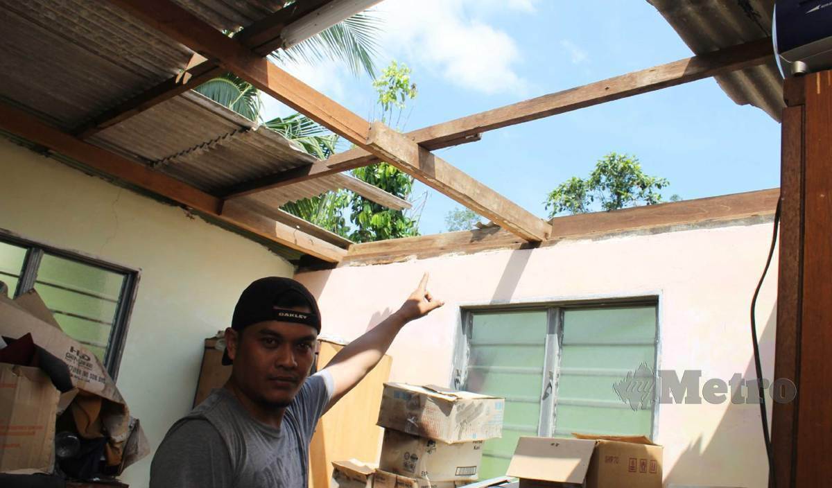 SYAHFIZIL Zuhairillah menunjukkan atap sebahagian rumah bapanya yang diterbangkan ribut di Kampung Kayu Ara Mambau. FOTO Mohd Amin Jalil