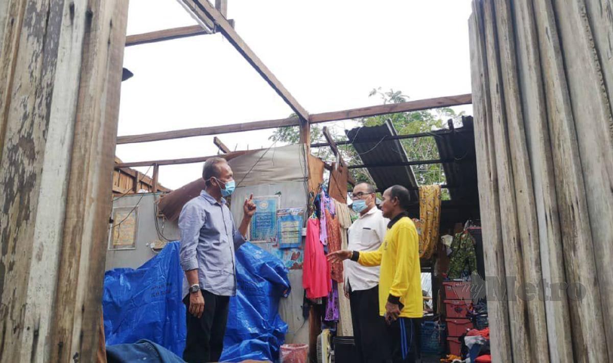 ZAWAWI (kanan) menceritakan kejadian bumbung rumahnya diterbangkan ribut kepada Wan Hassan (kiri). FOTO ihsan pembaca.