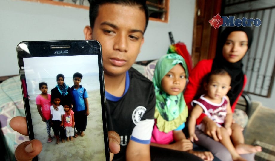 MOHD Shahrizal bersama ibu saudaranya, Siti Rosmaliza (kanan) dan adiknya,  Nor Shafikah menunjukkan foto bersama arwah ibu mereka. FOTO Farizul Hafiz Awang