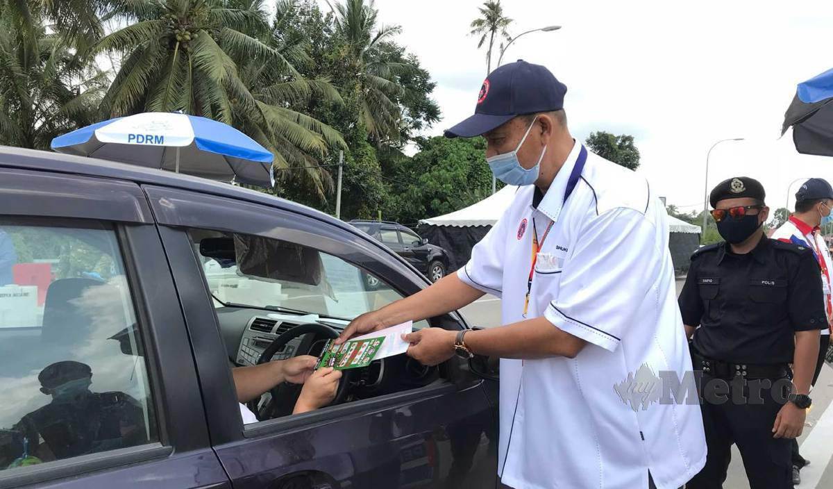 MUHAMMAD Shukri mengedarkan risalah pematuhan SOP Covid-19 kepada pengguna jalan raya di Jalan Pasir Mas- Salor.FOTO Hazira Ahmad Zaidi