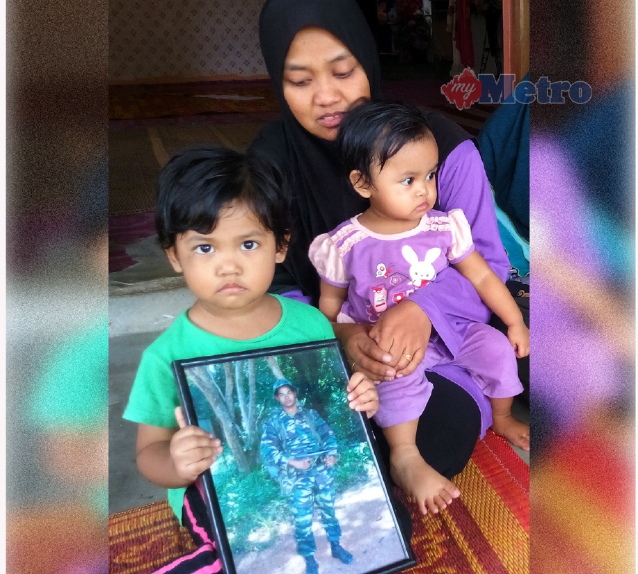 Nur Wasim Aqilah, 3, (kiri) memegang gambar bapanya Koperal Mohd Faizol Rosli yang hilang di laut di Pulau Perak dekat Langkawi, bersama ibunya Siti Aminah Abd Hamid, 30, dan adiknya Nur Maisara Saadiyyah, 1. - Foto Bernama